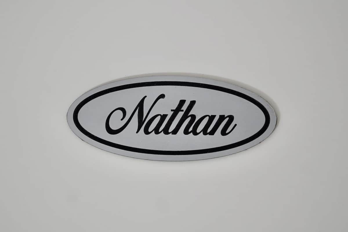 Un panneau ovale blanc portant le nom « Nathan » en caractères cursifs.