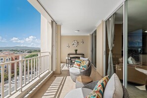 Un balcone con mobili in vimini, un tavolino con una pianta e vista sulla città.