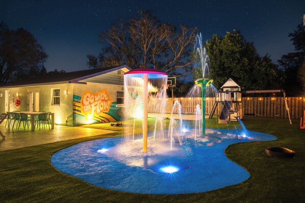 A backyard with a water fountain, a play area, and a building with a 'Gowish plus F' sign.