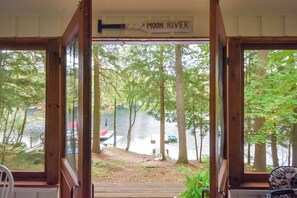 Eingang einer Holzhütte, ein Schild mit der Aufschrift 'Moon River' und dahinter ein See, umgeben von Bäumen.