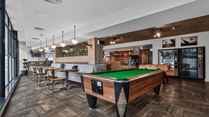 A pool table in a modern indoor setting with wooden flooring and pendant lighting. - Student Only The Parade (Cardiff)