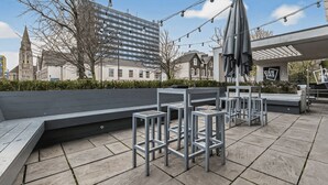 An outdoor seating area with modern chairs and tables, a bench, and a canopy umbrella. - Student Only The Parade (Cardiff)