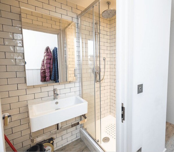 A bathroom with a glass shower enclosure, a white sink, and a mirror above it. - Student Only The Parade (Cardiff)