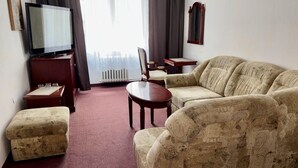 Ein Wohnzimmer mit einer Couch, einem Couchtisch, einem Fernseher und einer Heizung.