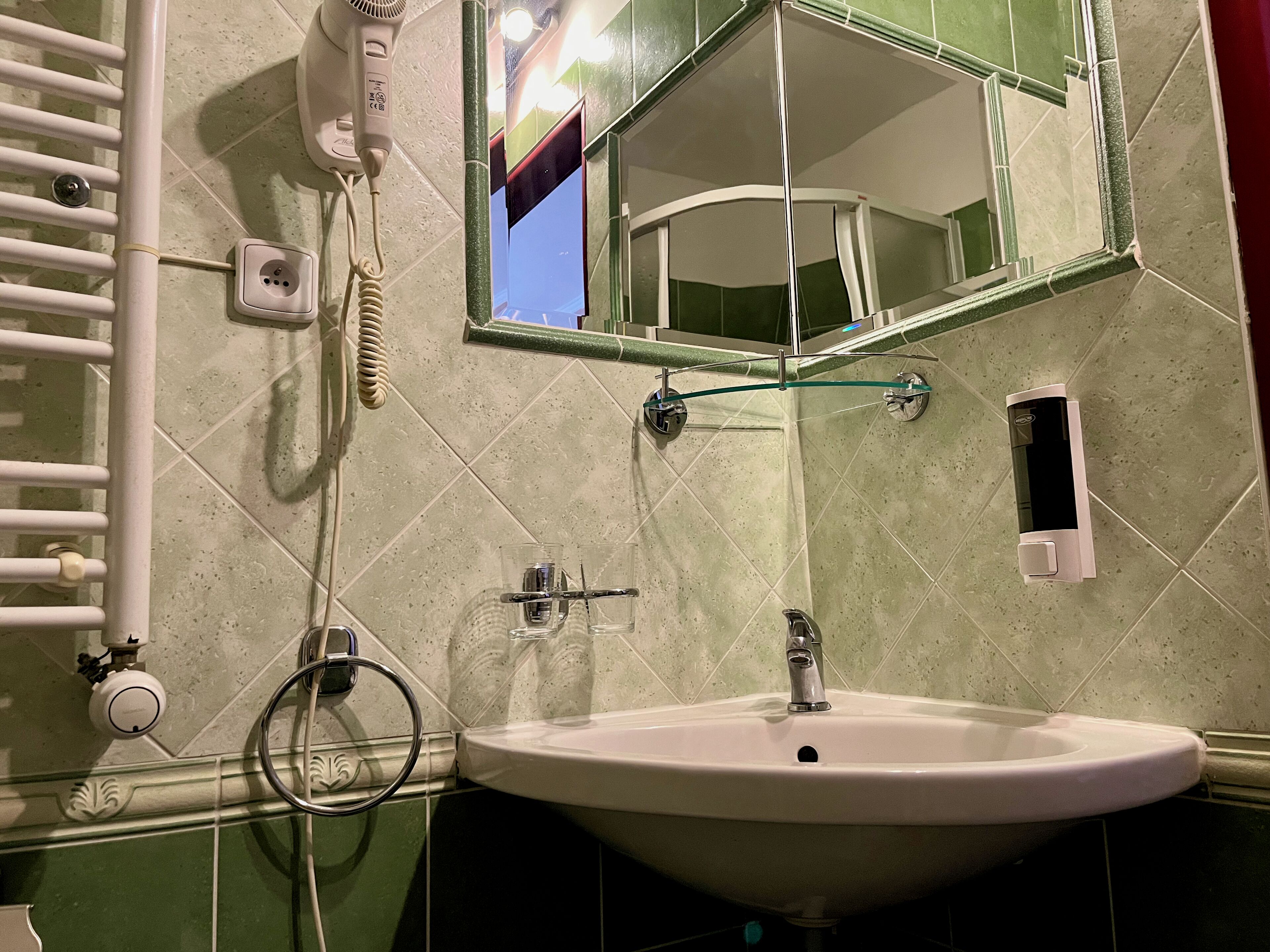 A bathroom with a sink, mirror, towel rack, and a hairdryer.