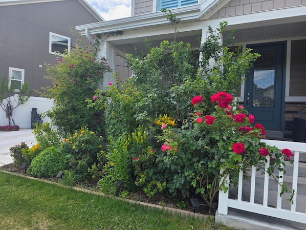 A residential house with a front porch, a well-maintained garden with various plants and flowers, and a clear sky. - Cozy Apt Near BYU UVU Canyon (Orem)