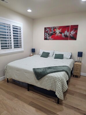 A bedroom with a bed, two bedside tables, a window with blinds, and a wall with two paintings. - Private Basement 1mi UVU 3 Parking (Orem)