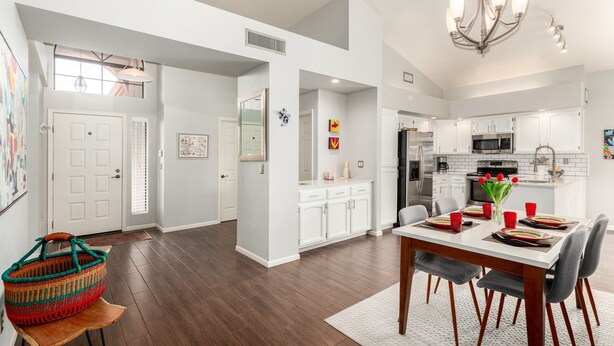 A modern kitchen with white cabinets, stainless steel appliances, and a dining area with a white table and chairs. - Cool & Comfy Tucson Summer Retreat w/ Yard (Tucson)