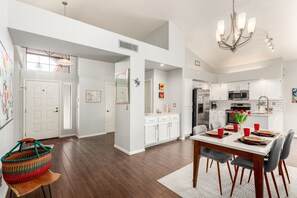 A modern kitchen with white cabinets, stainless steel appliances, and a dining area with a white table and chairs. - Cool & Comfy Tucson Summer Retreat w/ Yard (Tucson)