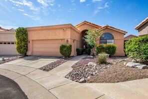 A residential house with a garage, a driveway, and a well-maintained garden with rocks and shrubs. - Cool & Comfy Tucson Summer Retreat w/ Yard (Tucson)