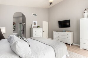 A bedroom with a bed, a dresser, a television, and a door. - Cool & Comfy Tucson Summer Retreat w/ Yard (Tucson)
