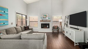 A living room with a sofa, fireplace, TV, and artwork. - Cool & Comfy Tucson Summer Retreat w/ Yard (Tucson)