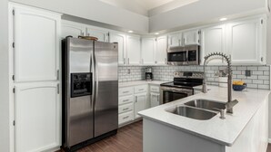 A modern kitchen with white cabinets, stainless steel appliances, a double sink, and a microwave. - Cool & Comfy Tucson Summer Retreat w/ Yard (Tucson)