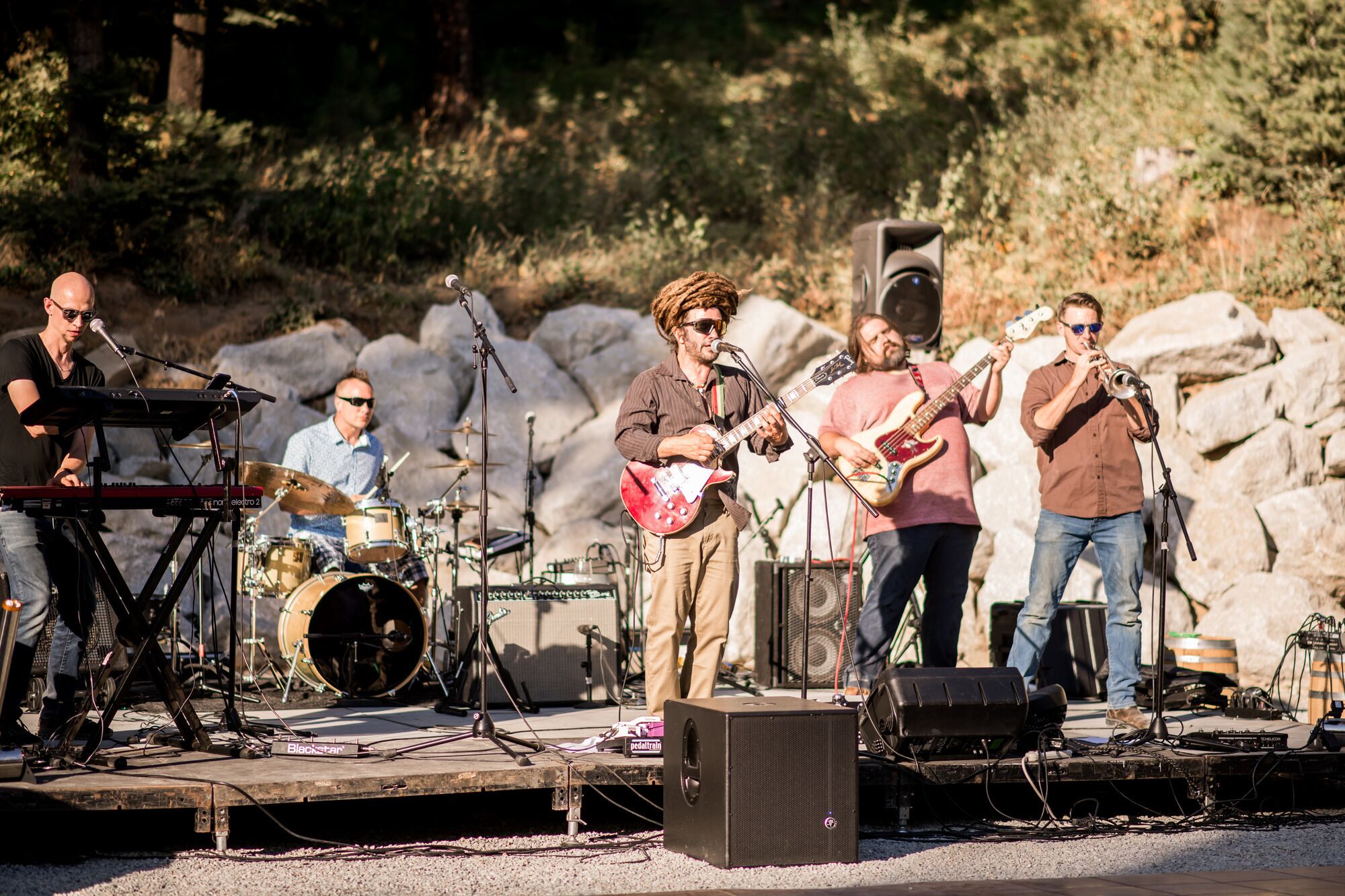 A band performing on an outdoor stage with musical instruments and equipment.