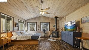 L’intérieur chaleureux d’un chalet avec un plafond en bois, un lit offrant une belle vue, une cheminée et un grand tableau.