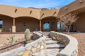 A building with a curved staircase, a cactus, and a stone wall.