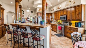 Une cuisine spacieuse avec des meubles en bois, un îlot central doté de tabourets et des appareils électroménagers modernes.