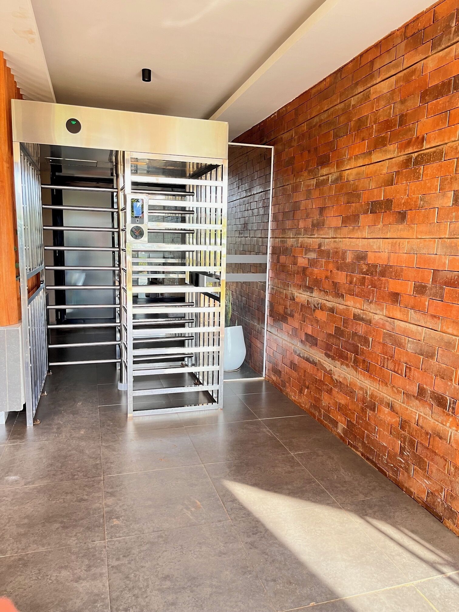 A room with a brick wall, a metal rack with trays, and a white ceiling.