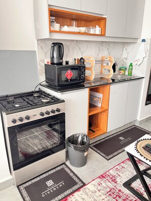 Cocina compacta con estufa, horno, microondas y un espacio para café.