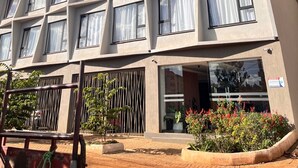 A multi-story hotel with a geometric facade, large windows, and a gated entrance. - Scenic Studio Escape with Parking in Kiambu Rd (Kiambu)