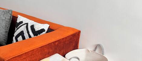 Une table de chevet en bois avec un tiroir, un panier en osier blanc et une serviette blanche pliée.