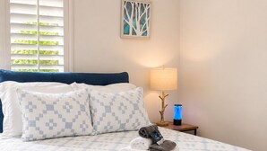Un lit bien fait, avec une couvre-lit à motifs, un oreiller et une serviette pliée posée sur le lit.