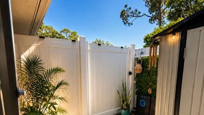 A patio with a white fence, potted plants, and a tiled floor.