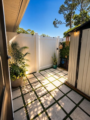 A patio with a white fence, potted plants, and a tiled floor.