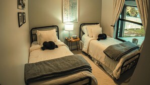 Une chambre avec deux lits, un ventilateur de plafond, une carte accrochée au mur et une fenêtre avec des rideaux.