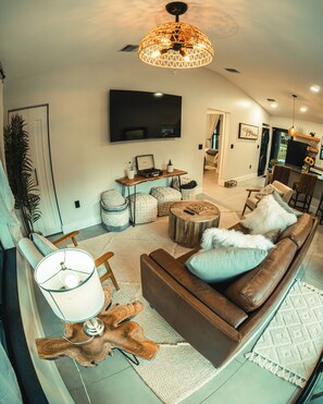 A modern living room with a brown leather sofa, a wooden coffee table, and a large flat-screen TV mounted on the wall. - Casita Verde 2-br guest house under an oak canopy, ideal spot in Palm Beach G... (Palm Beach Gardens)