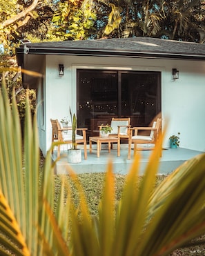 Una casa moderna con un patio amueblado con muebles de madera y plantas en macetas.