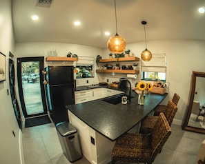 Una cocina moderna con una isla central, iluminación colgante y vistas al exterior.