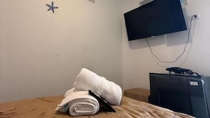 A hotel room with a bed, an air conditioner, a flat-screen TV mounted on the wall, and a star decoration on the wall. - Davé Paradise (Cartagena)