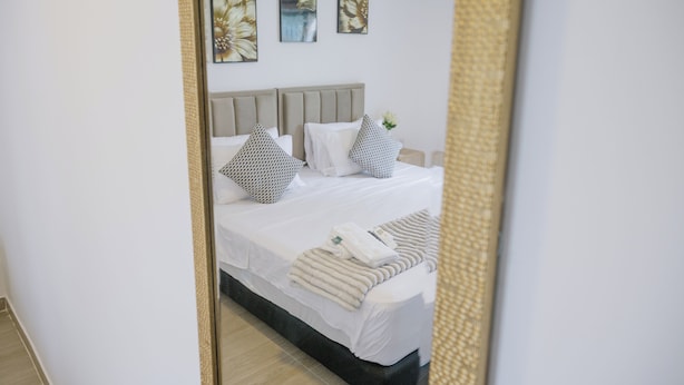 A neatly made bed with white linens and a folded towel, a grey headboard, and three floral wall art pieces. - Davé Paradise (Cartagena)
