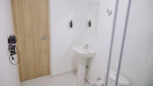 A bathroom with a wooden door, a white sink, a mirror, and a toilet. - Davé Paradise (Cartagena)