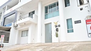 A white building with a balcony, a door labeled "26-113," and a parking sign. - Davé Paradise (Cartagena)