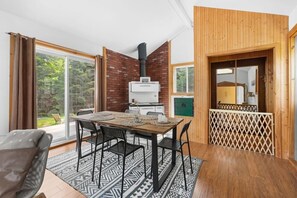 Een moderne keuken met een inbouwfornuis, een eethoek met een houten tafel en stoelen, en grote ramen met uitzicht op de omgeving.