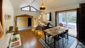 Un salón amplio con una mesa de comedor de madera, un sofá y un ventanal que ofrece vistas al exterior.