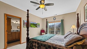 A bedroom with a bed, a ceiling fan, a window with curtains, a clock, and a door leading to another room. - Fairway & Mountain Views, Relaxing 2BR Condo Retreat (Whittier)