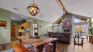 A spacious living area with a wooden dining table, a fireplace, and a large window overlooking a scenic view. - Fairway & Mountain Views, Relaxing 2BR Condo Retreat (Whittier)