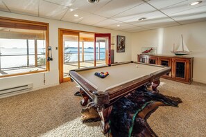 A pool table in a room with a view of the water, a wooden cabinet, and a door leading outside. - Hot Tub & Whale Watching! Scenic Sitka Escape (Sitka)