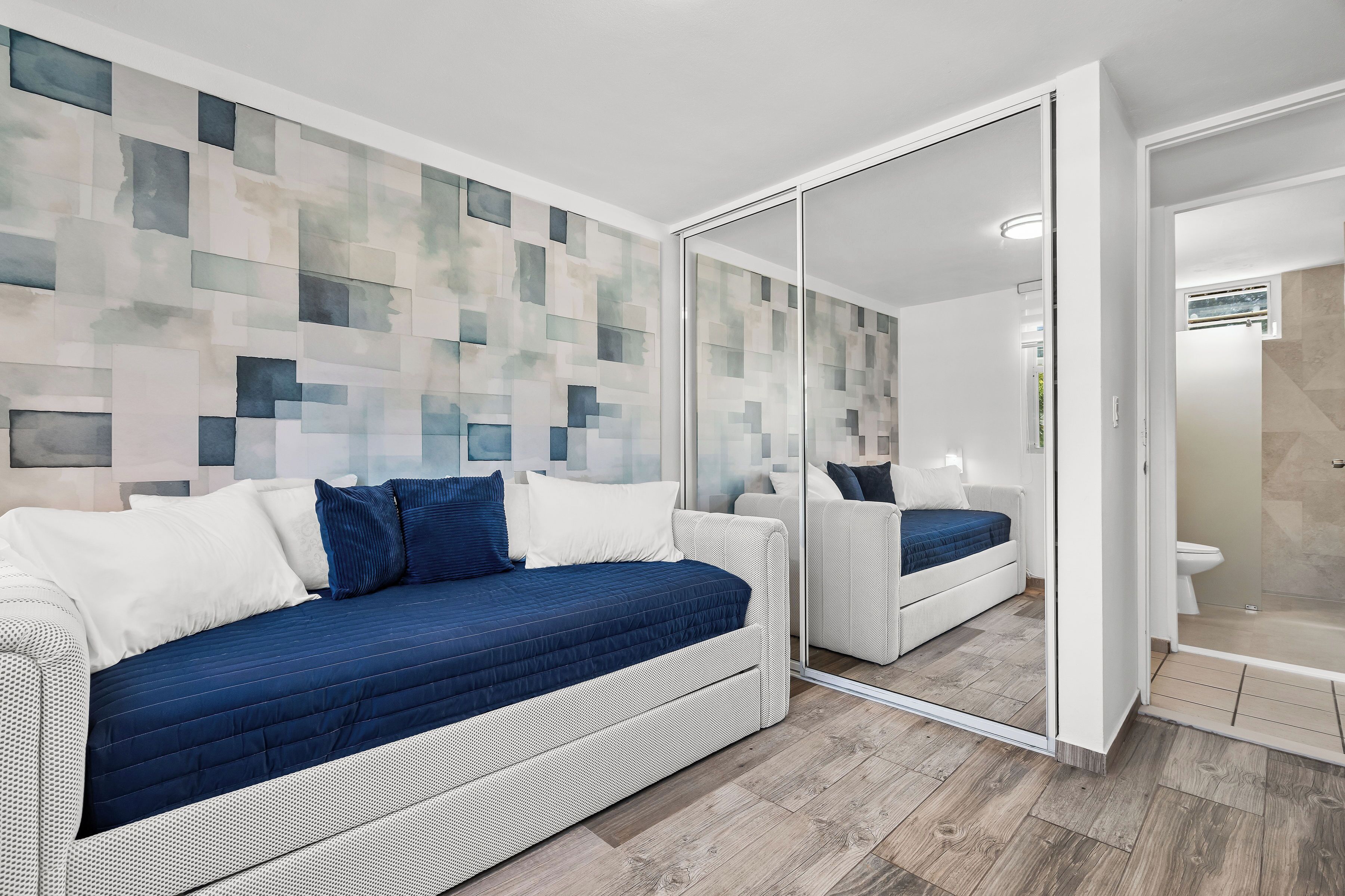 Un dormitorio moderno con un espejo grande, un sofá cama y una zona de ducha.