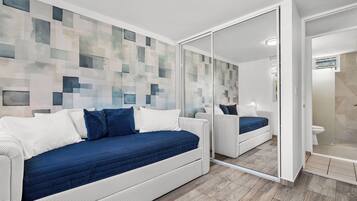 Un dormitorio moderno con un espejo grande, un sofá cama y una zona de ducha.