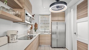 Une cuisine moderne avec des meubles en bois, un réfrigérateur en acier inoxydable et un four encastré.