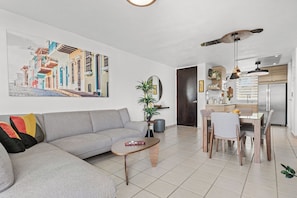 Una sala de estar moderna con un sofá gris, una mesa de centro de madera y una zona de comedor con una mesa y sillas de madera.