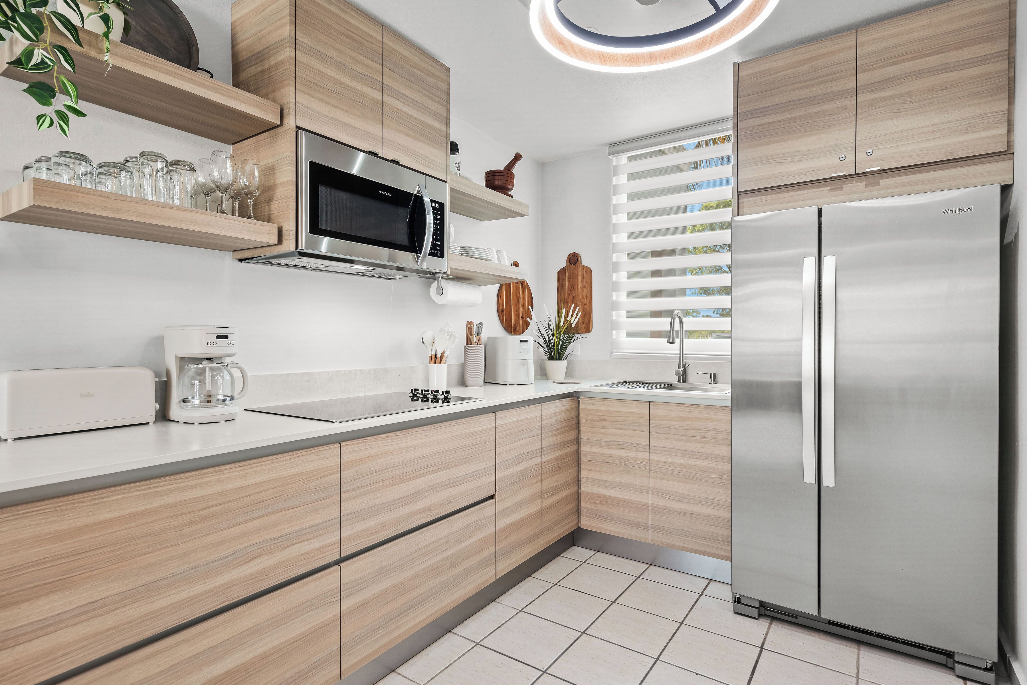 Una cocina moderna con armarios de madera, un refrigerador de acero inoxidable, un microondas integrado y una cafetera.