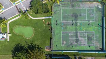 Vista aérea de un complejo deportivo con cancha de tenis, campo de golf y zonas verdes circundantes.
