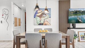 Un espace repas moderne avec une table en bois, des chaises grises et des luminaires suspendus.