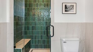Ein Badezimmer mit grünen Fliesen, einer weißen Toilette und einem gerahmten Bild an der Wand.