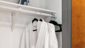 A white robe hanging on a rack in a bathroom with a wooden door and a white towel rack.